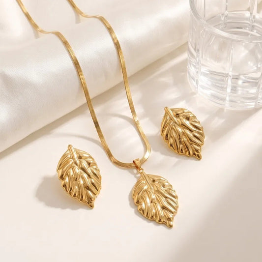 Aramat Jewels goudkleurige RVS sieradenset met een slangenketting en bijpassende oorbellen in bladvorm.