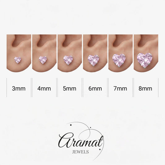 Aramat Jewels hartjes oorstekers met roze zirkonia in zilverkleurig RVS, getoond in zes verschillende maten.