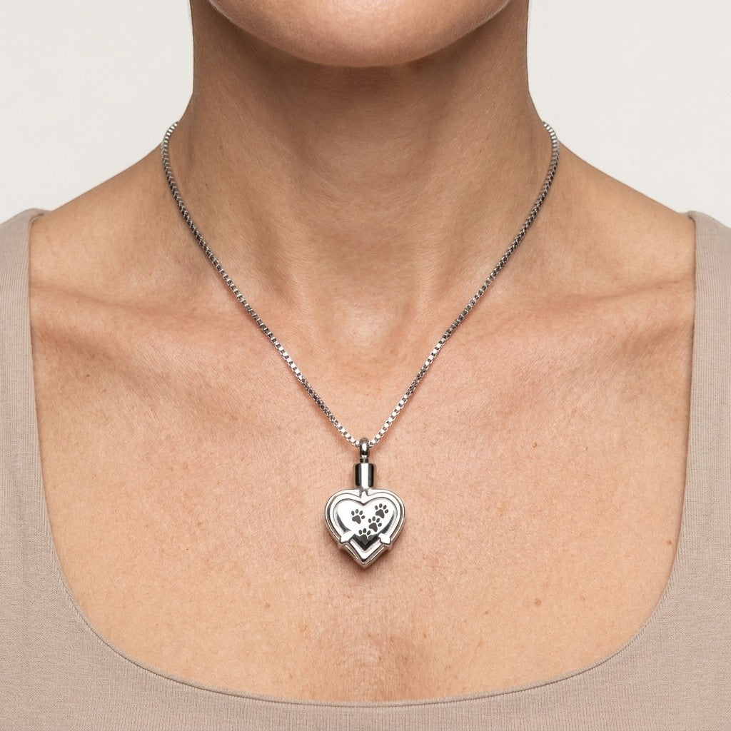 Aramat Jewels zilverkleurige hartvormige ashanger met pootafdrukken, gemaakt van roestvrij staal.