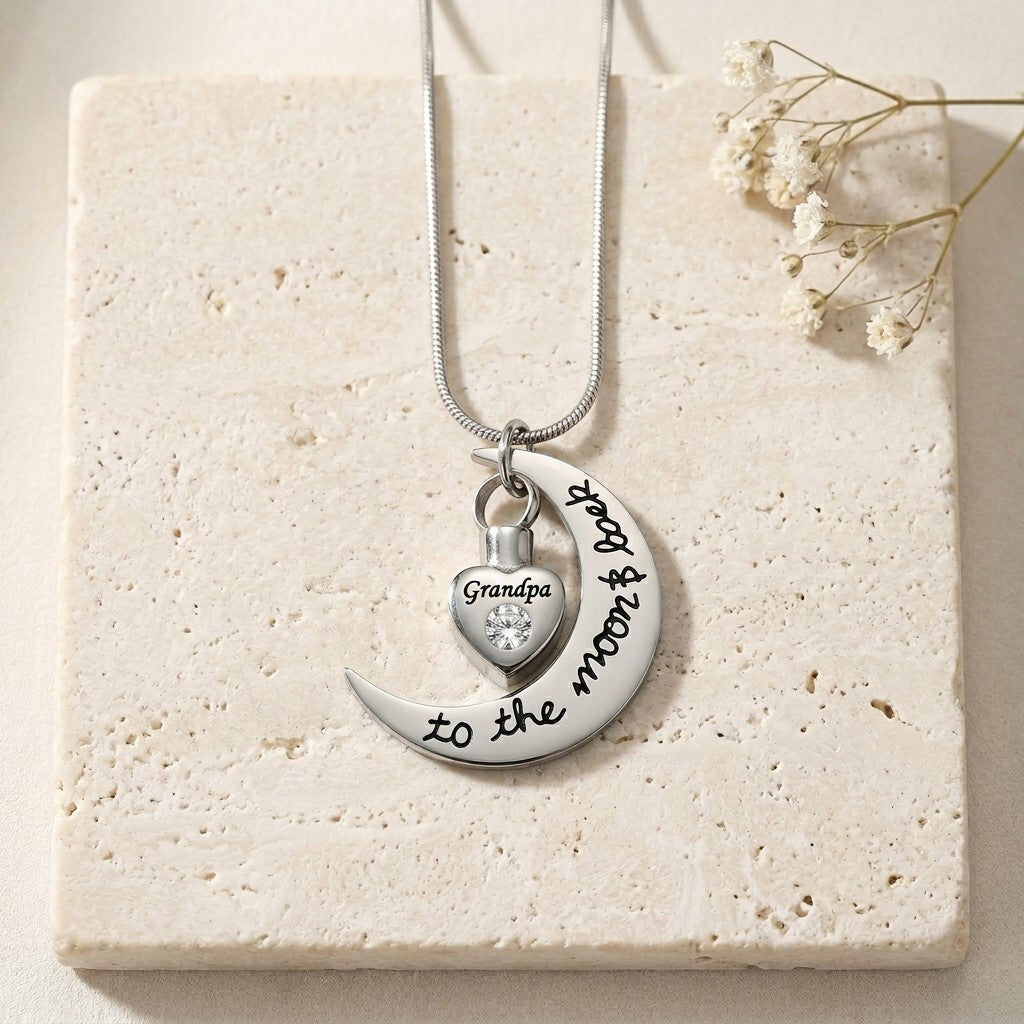 Aramat Jewels ashanger met de tekst "Grandpa to the moon and back" op een halve maan, met een hartvormig urn-hangertje met zirkonia.