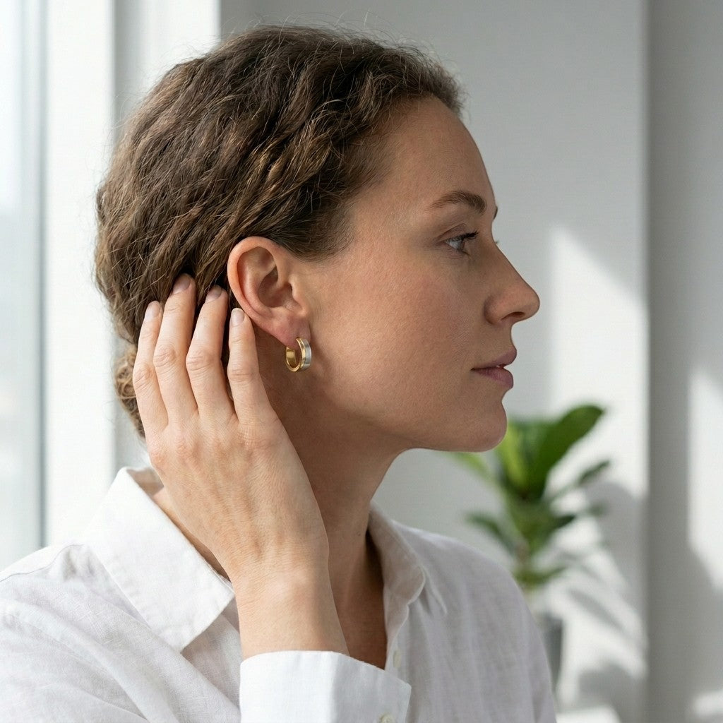 Aramat Jewels bicolor hoop earrings with matte silver and gold stripes, 13mm, worn by a woman.