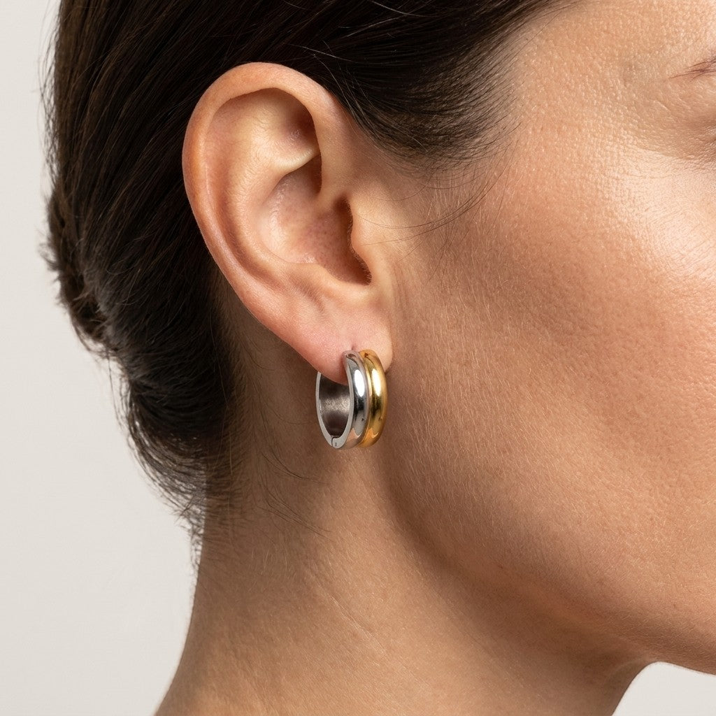Aramat Jewels bicolor stainless steel hoop earrings, a mix of gold and silver tones, worn by a model.