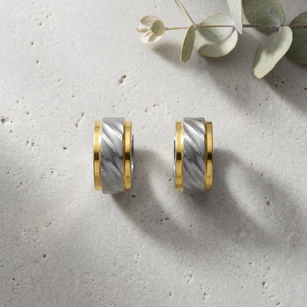 Aramat Jewels bicolor huggie hoop earrings in gold and silver stainless steel with a sandblasted diagonal stripe design.