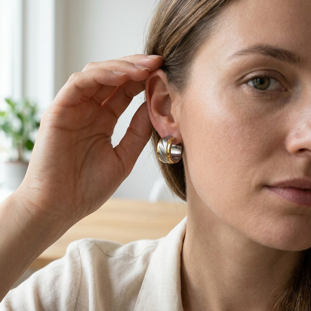 Aramat Jewels bicolor huggie hoop earrings in gold and silver stainless steel with a sandblasted striped design.