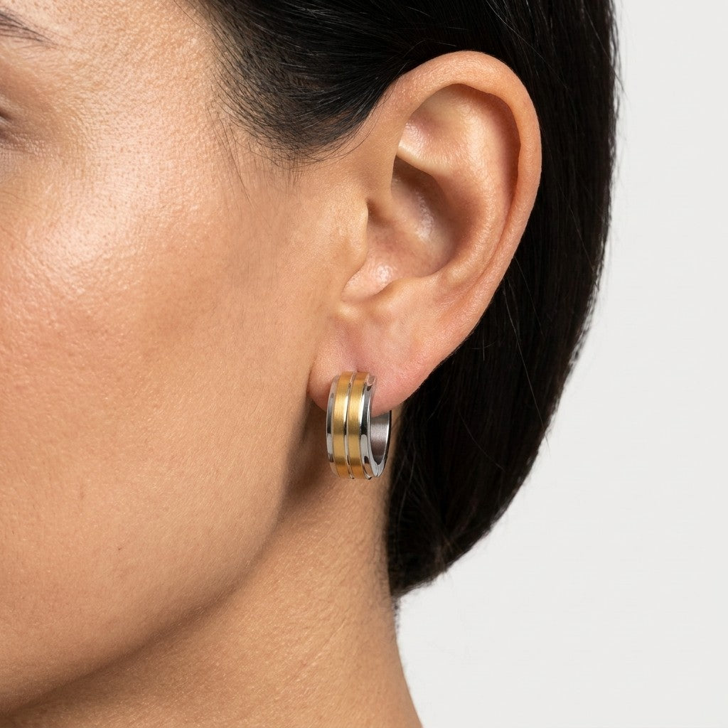 Aramat Jewels stainless steel huggie hoop earrings, 13mm, with a bicolor design featuring two thin gold stripes on a silver base.