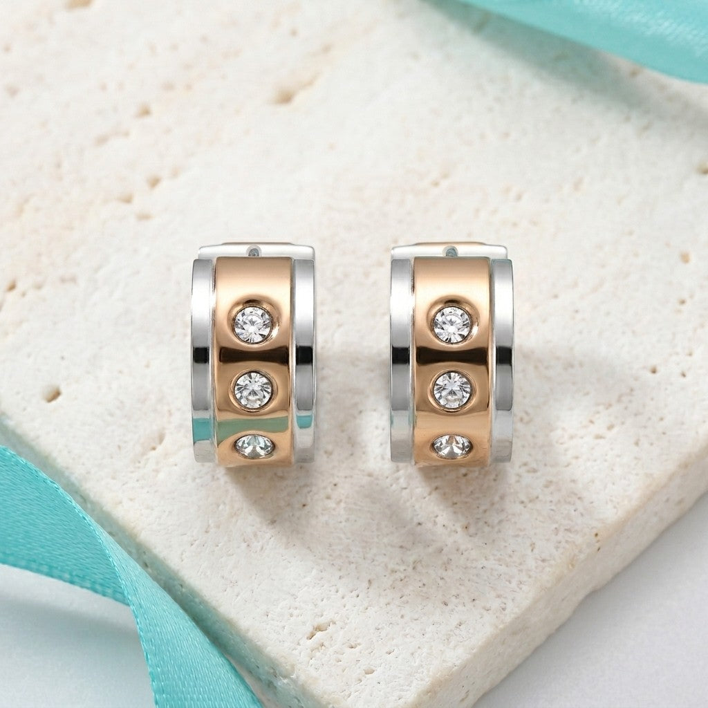 Aramat Jewels bicolor stainless steel huggie hoop earrings with three clear cubic zirconia stones each.