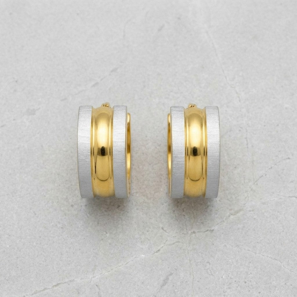 Aramat Jewels bicolor RVS huggie hoop earrings with a matte silver exterior and a polished gold interior.