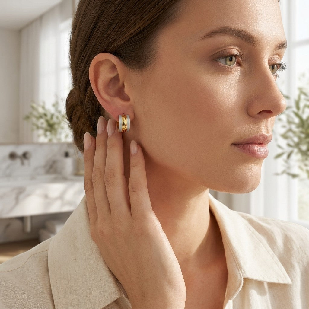 Aramat Jewels bicolor RVS huggies earrings with matte silver and gold accents worn by a woman.