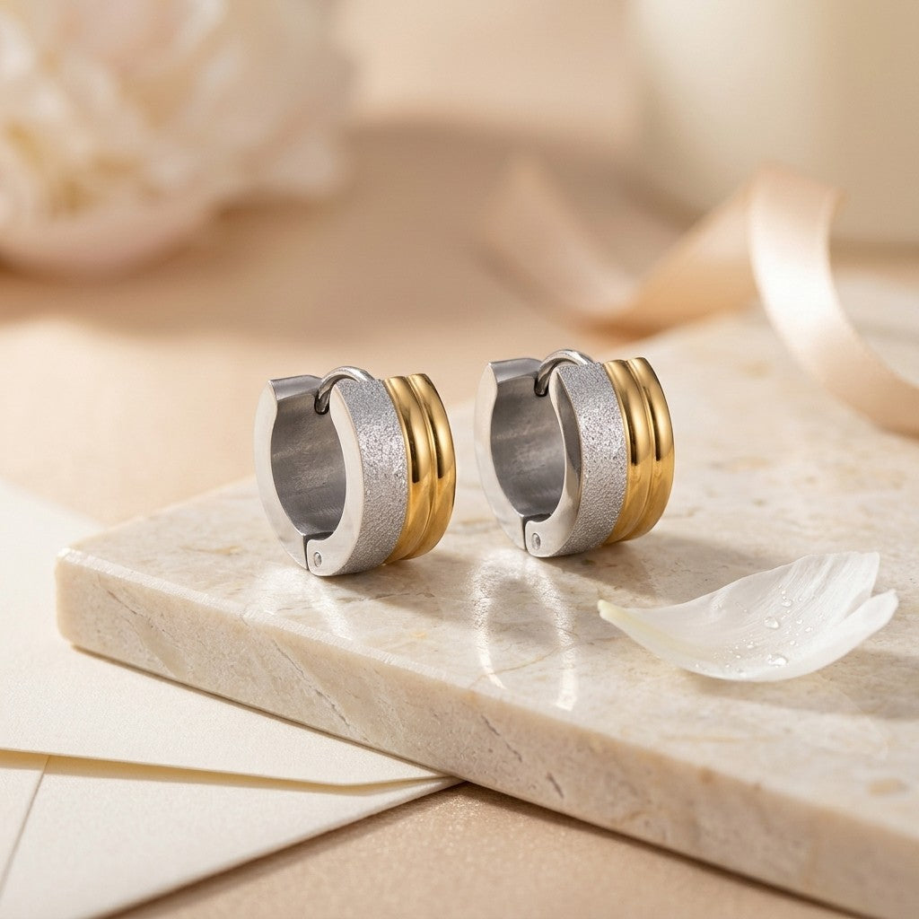 Aramat Jewels bicolor huggie hoop earrings in stainless steel with matte silver and shiny gold stripes, 13mm diameter.