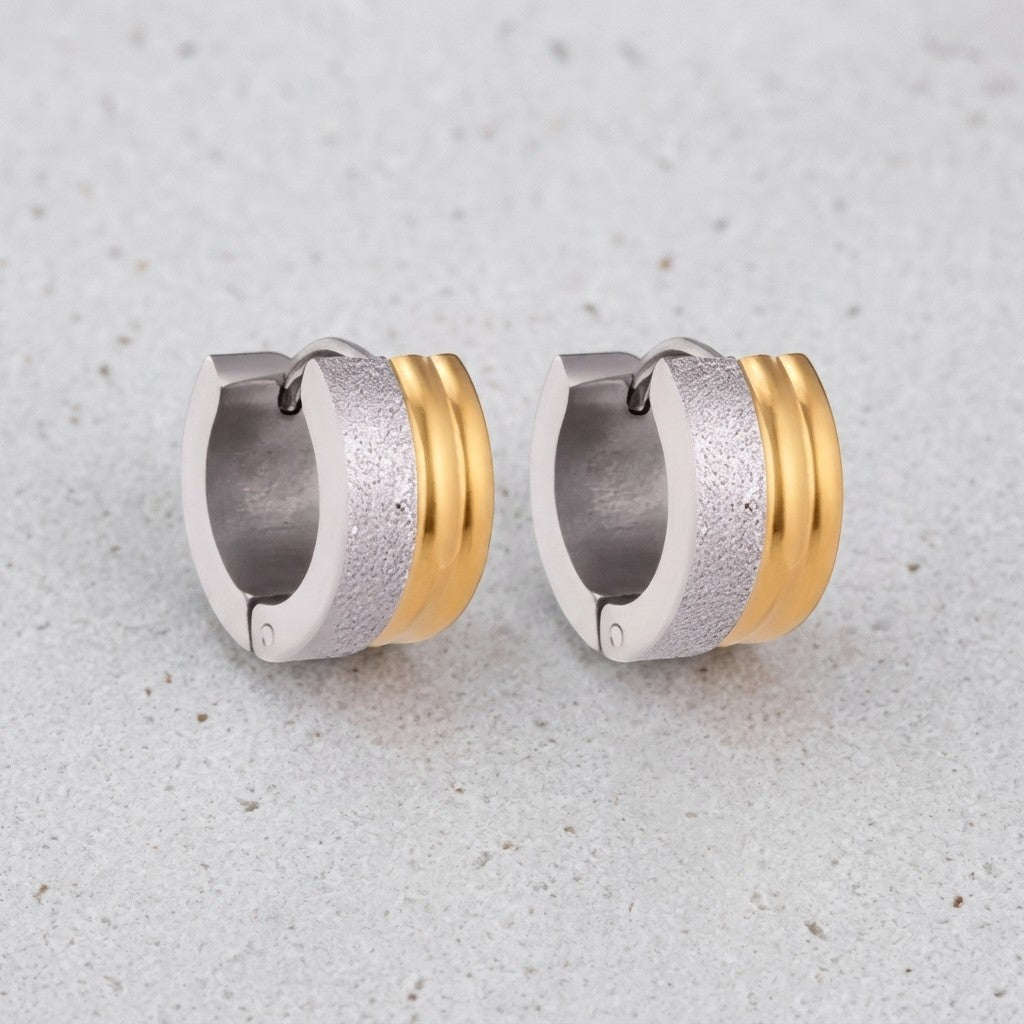 Aramat Jewels bicolor huggie hoop earrings in stainless steel with matte silver and shiny gold stripes, 13mm diameter.