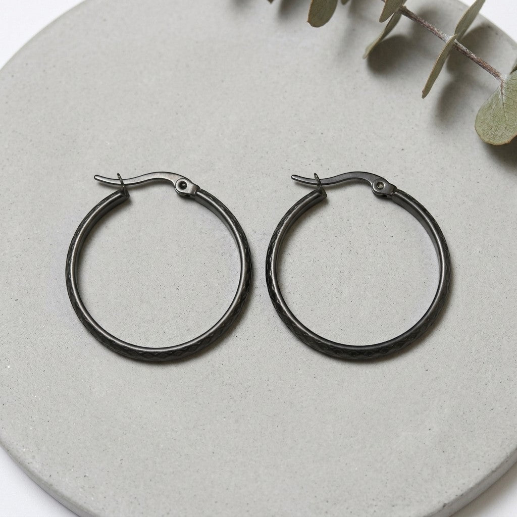 Aramat Jewels black stainless steel hoop earrings with a 30mm diameter and a subtle diamond pattern.