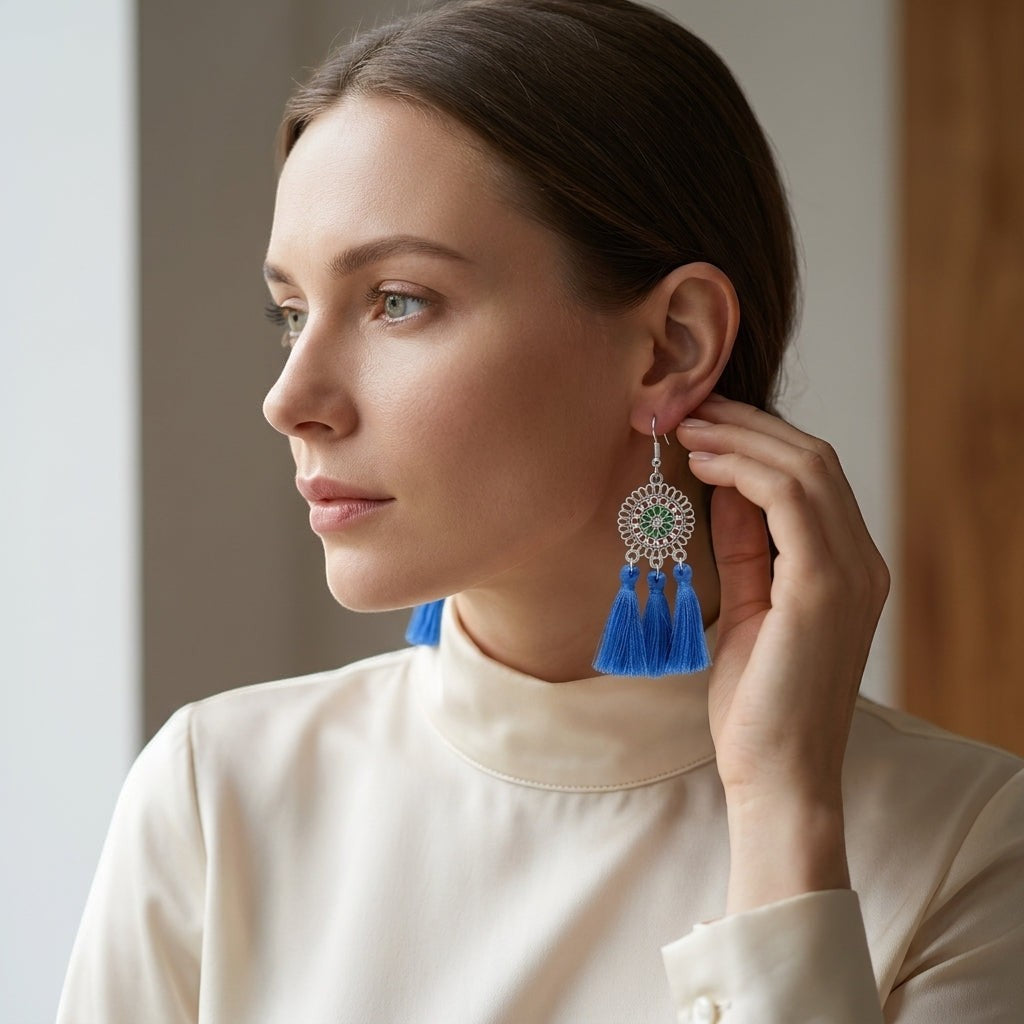 Aramat Jewels blue boho tassel earrings made of stainless steel worn by a woman in a cream-colored top.