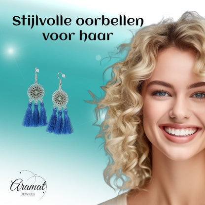 Aramat Jewels blue boho dangle earrings with three tassels and stainless steel accents worn by a smiling woman.