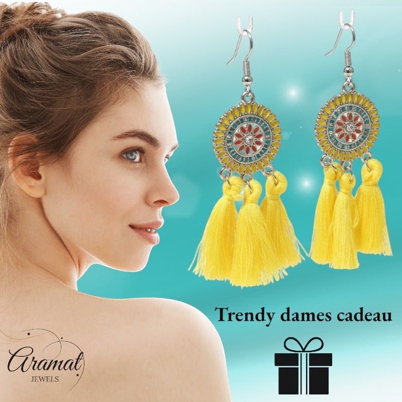 Aramat Jewels boho oorhangers met gele kwastjes en emaille details, gedragen door een vrouw voor een zomerse look.