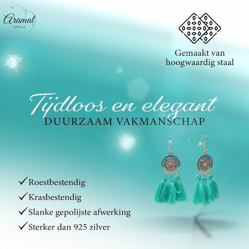 Aramat Jewels boho oorhangers met mintgroene kwastjes en roestvrijstalen details op een turquoise achtergrond.