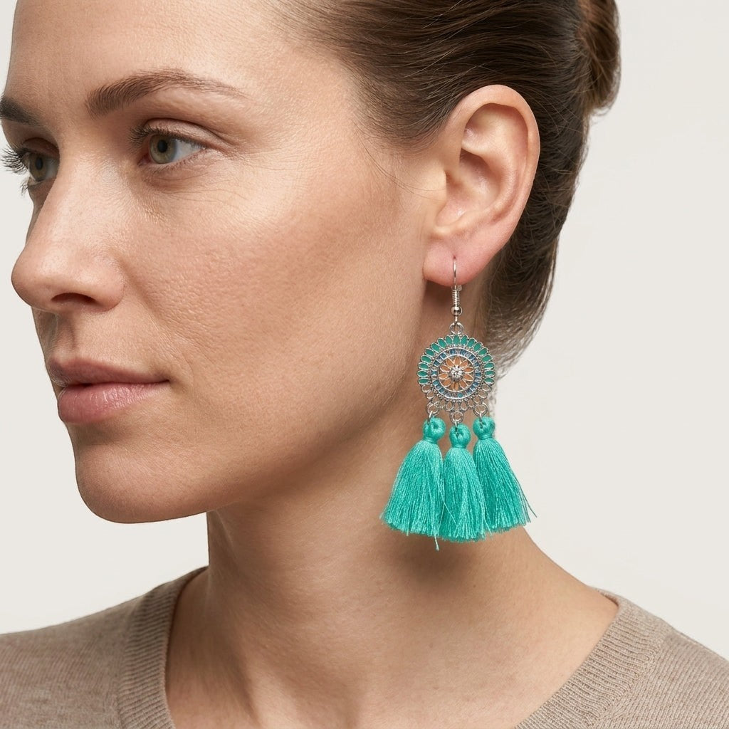 Model draagt Aramat Jewels boho oorhangers met mintgroene kwastjes en zilverkleurig RVS met emaille details.