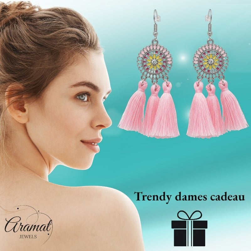 Aramat Jewels boho oorhangers met roze kwastjes, emaille details en roestvrij staal, gedragen door een model.