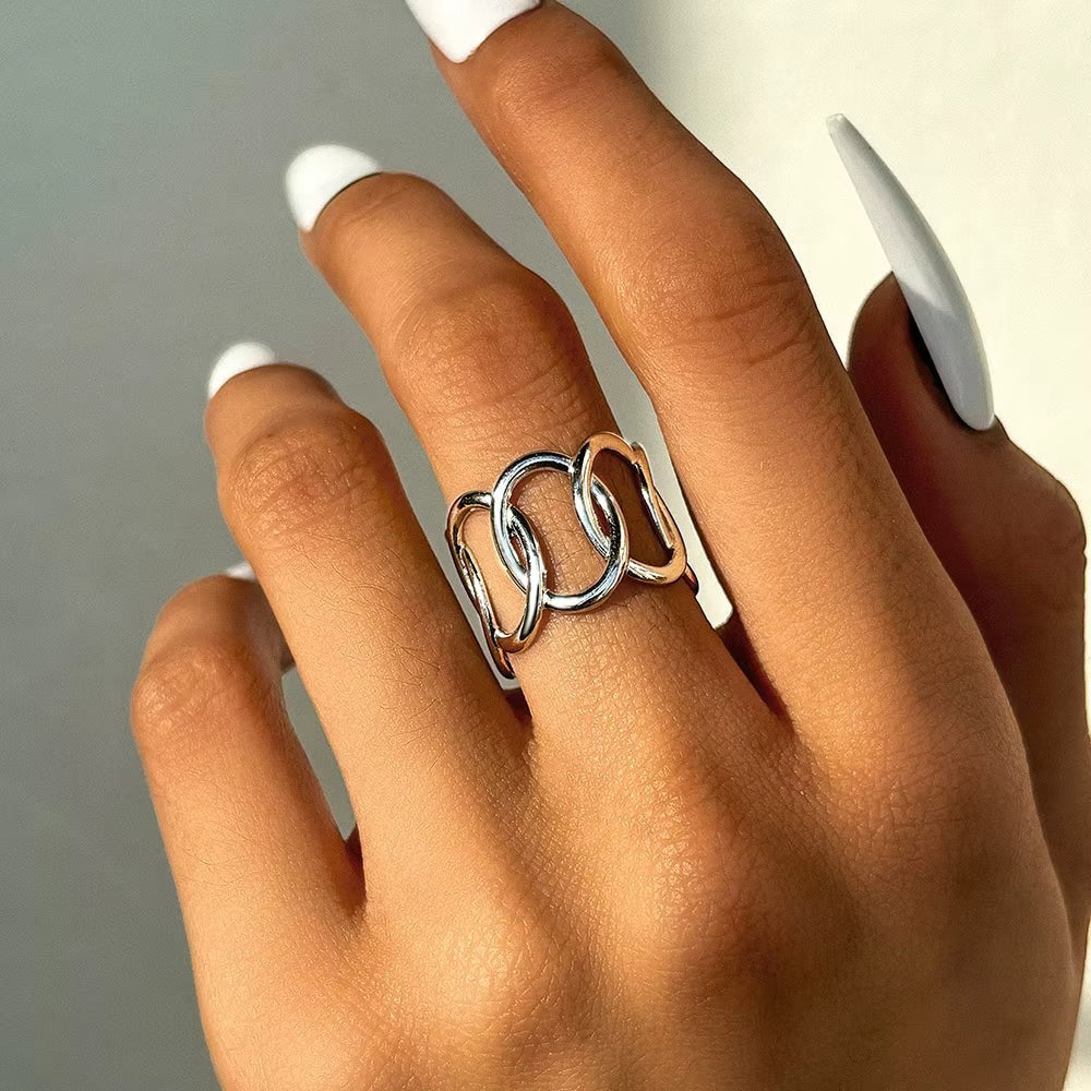Aramat Jewels brede zilverkleurige RVS ring met open ovale schakels, gedragen om een vinger met witte nagels.