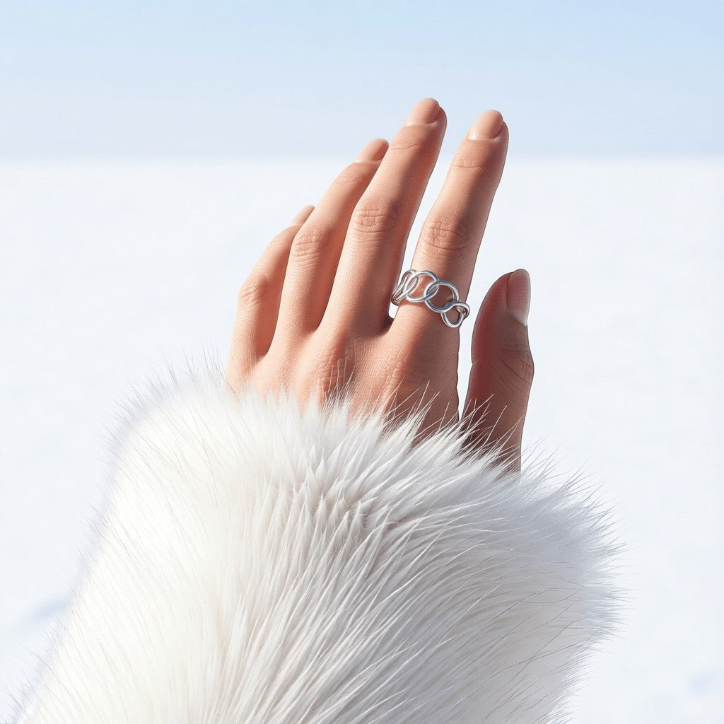 Aramat Jewels brede zilverkleurige RVS ring met ovale schakels gedragen aan een hand met witte bontmanchet.