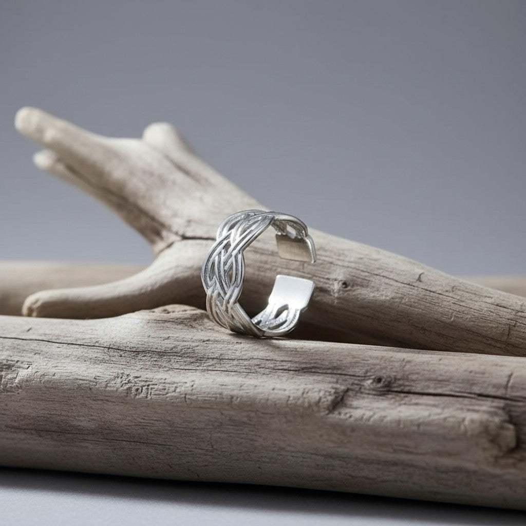 Aramat Jewels adjustable silver-colored stainless steel ring with an intricate Celtic braided knot design on driftwood.