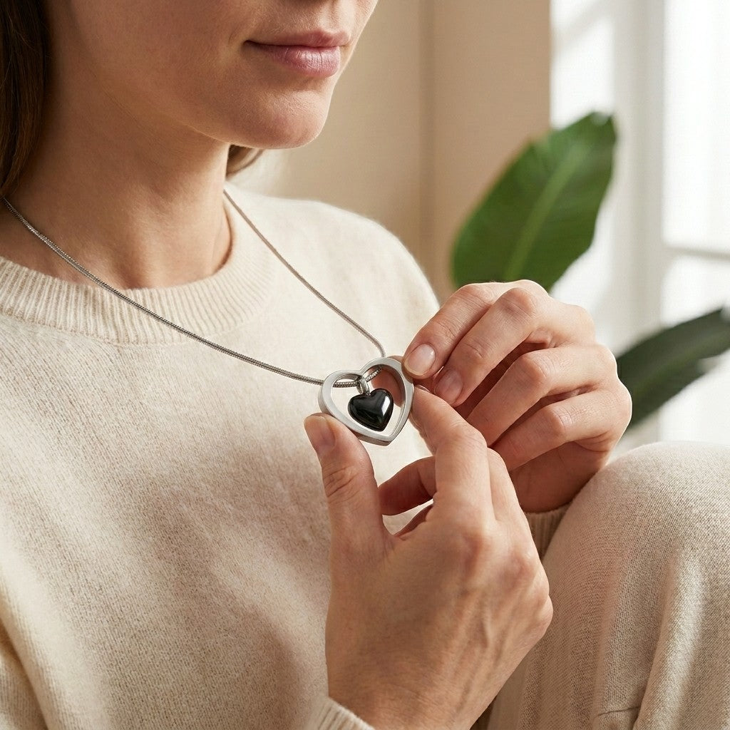 Aramat Jewels Zwart Hartje Stalen Crematiehanger met een zwart hartje binnen een zilverkleurig hartvormig frame.