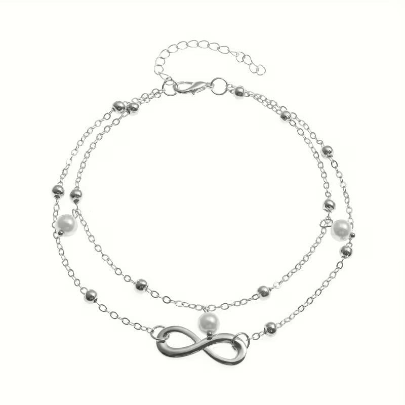 Aramat Jewels dubbel enkelbandje in zilverkleur met infinity symbool en witte parels voor een zomerse look.