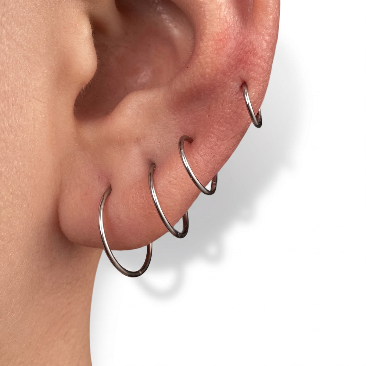 Aramat Jewels dunne zilverkleurige RVS oorringen gedragen in meerdere gaatjes in een oor voor een minimalistische look