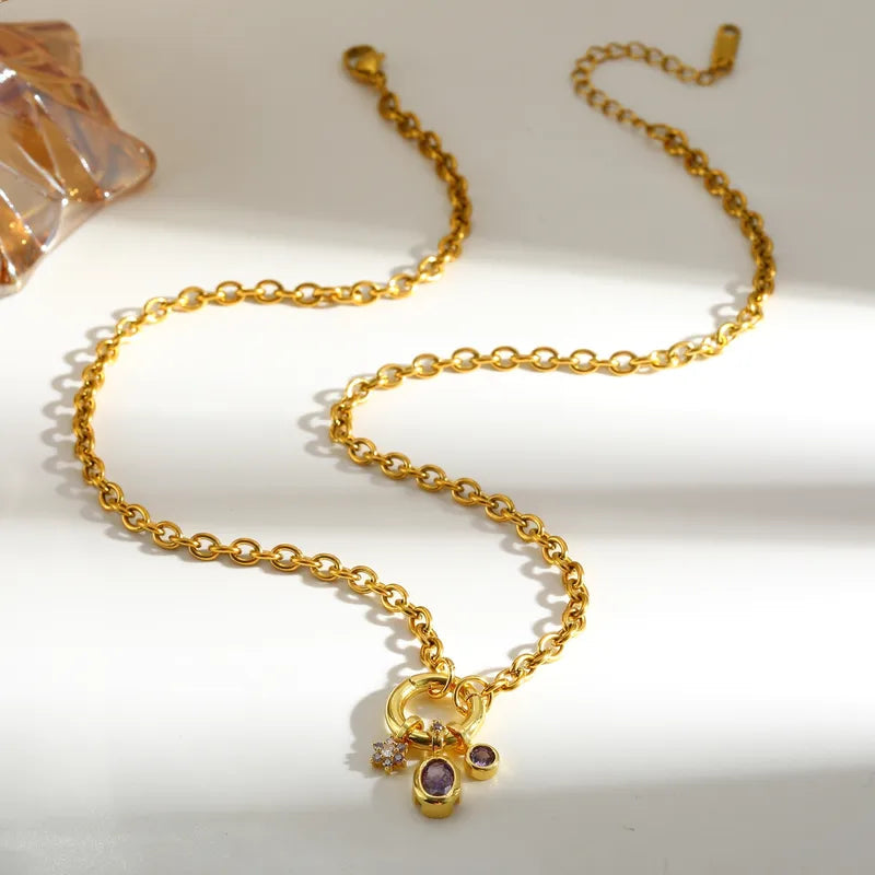 Aramat Jewels gold-colored stainless steel anchor chain necklace with a charm ring and three purple zirconia pendants.