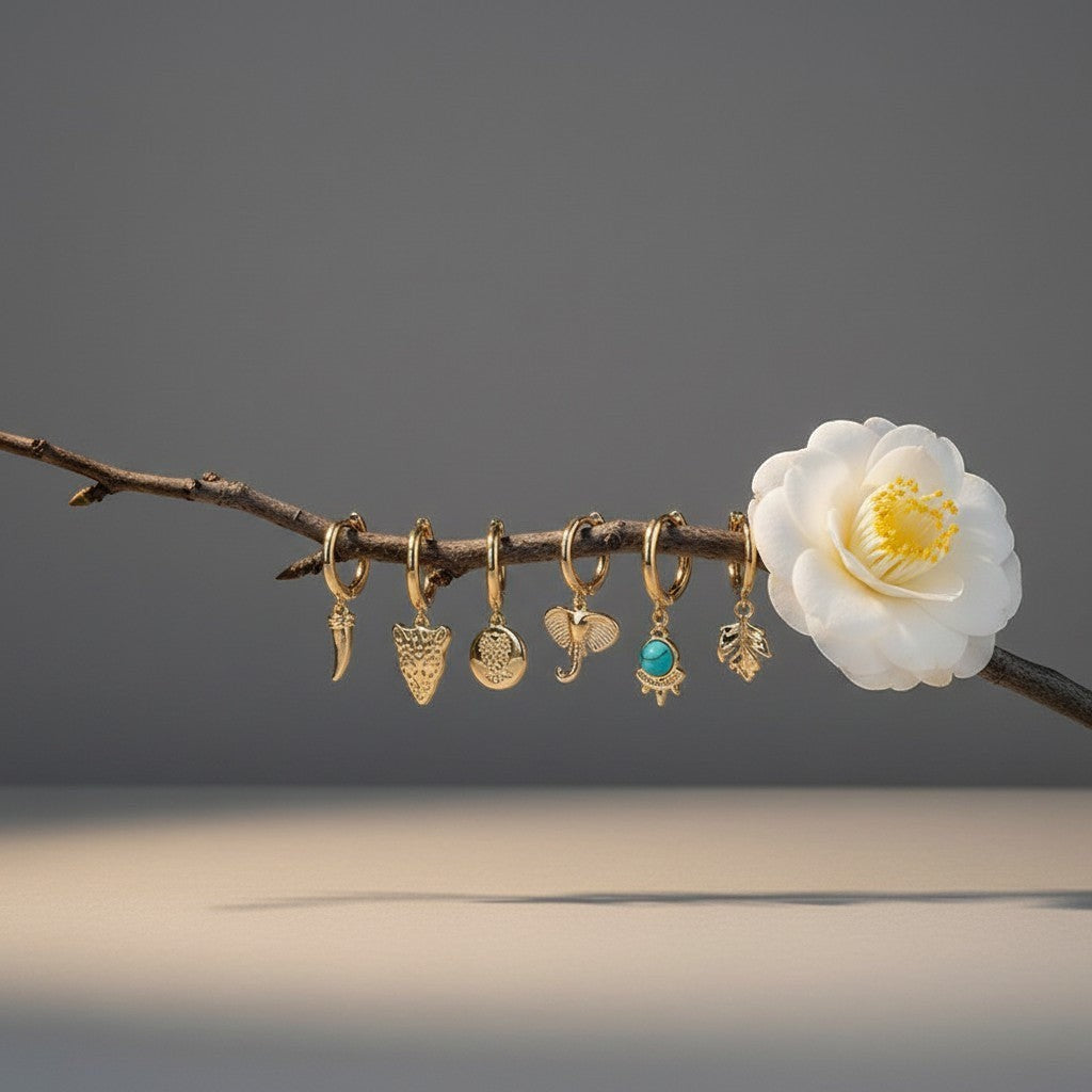 Aramat Jewels set of 6 gold-plated hoop earrings with animal charms: horn, leopard, owl, elephant, turquoise stone, and leaf.