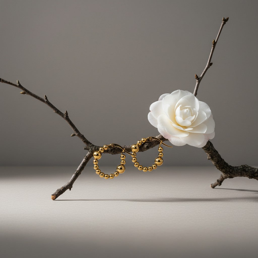 Aramat Jewels gold-tone stainless steel hoop earrings with a beaded pattern and two larger accent beads.