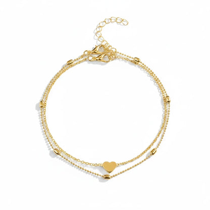 Aramat Jewels gold-tone double-layered stainless steel anklet featuring a heart charm and delicate beads.