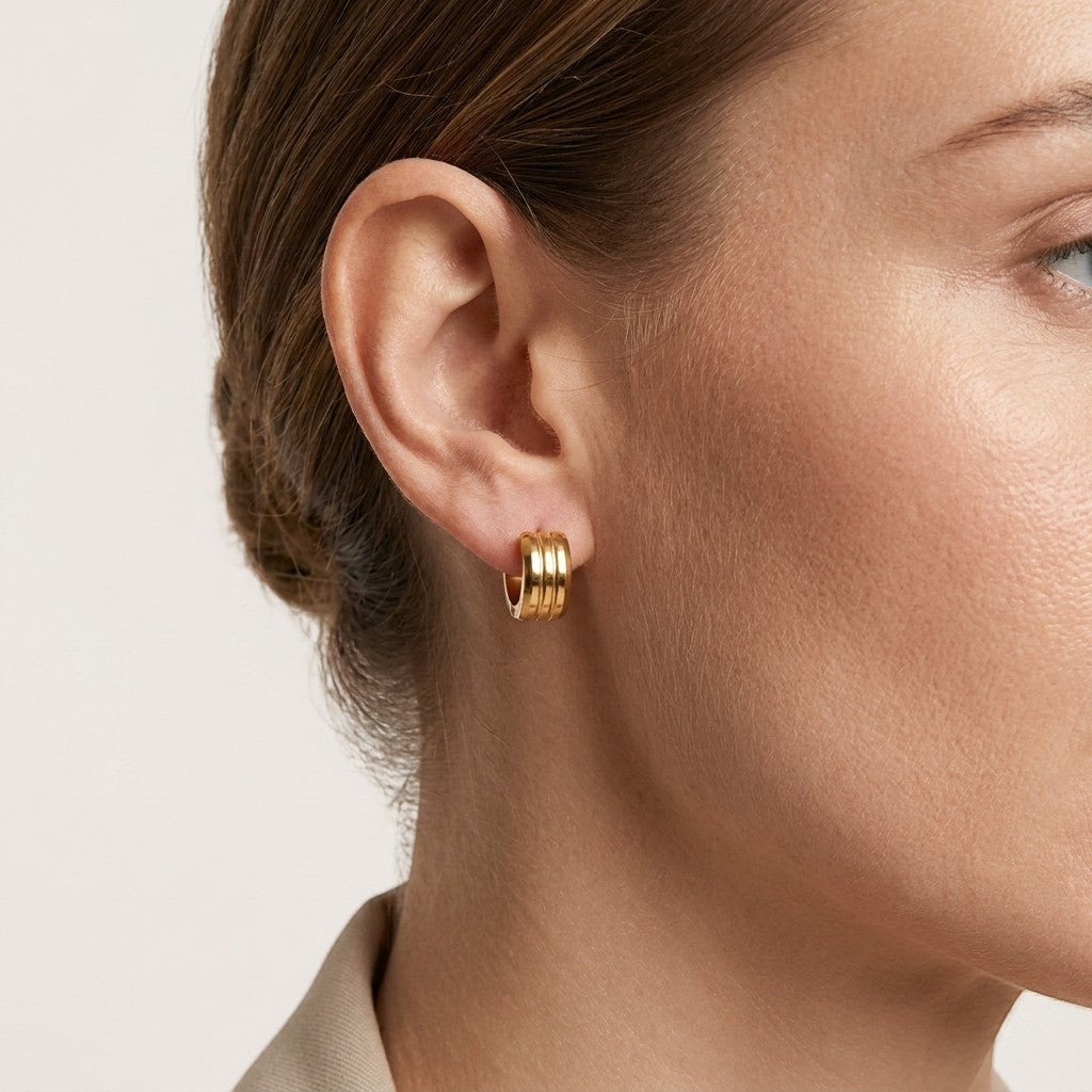 Aramat Jewels gold-tone stainless steel hoop earrings with double stripe detail, worn by a model.
