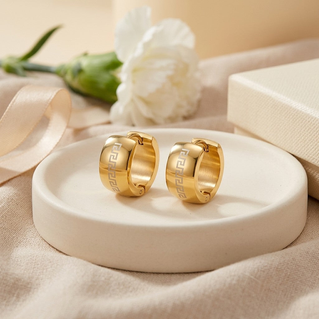 Aramat Jewels gold-tone stainless steel hoop earrings with engraved Greek key pattern, 13mm diameter.