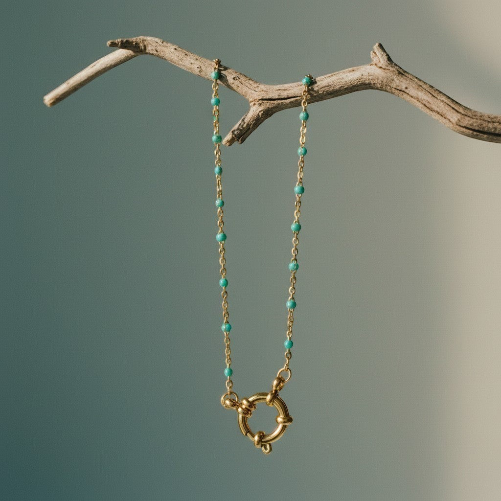 Aramat Jewels gold chain necklace with small green enamel beads and a large gold clasp with knot detail.
