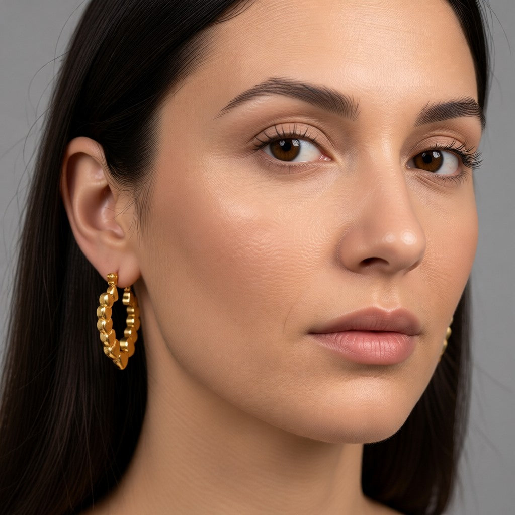 Aramat Jewels gold-coloured stainless steel hoop earrings with a heart motif, featuring a drop shape and a hinge closure.