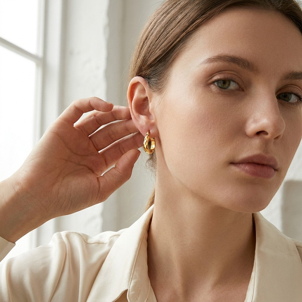 Aramat Jewels small gold-tone stainless steel hoop earrings with flattened facets, 10mm diameter.