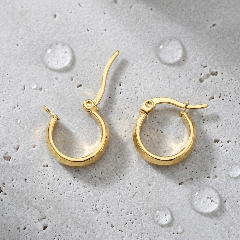 Aramat Jewels small gold-colored stainless steel hoop earrings with a faceted block pattern and a hinge closure.