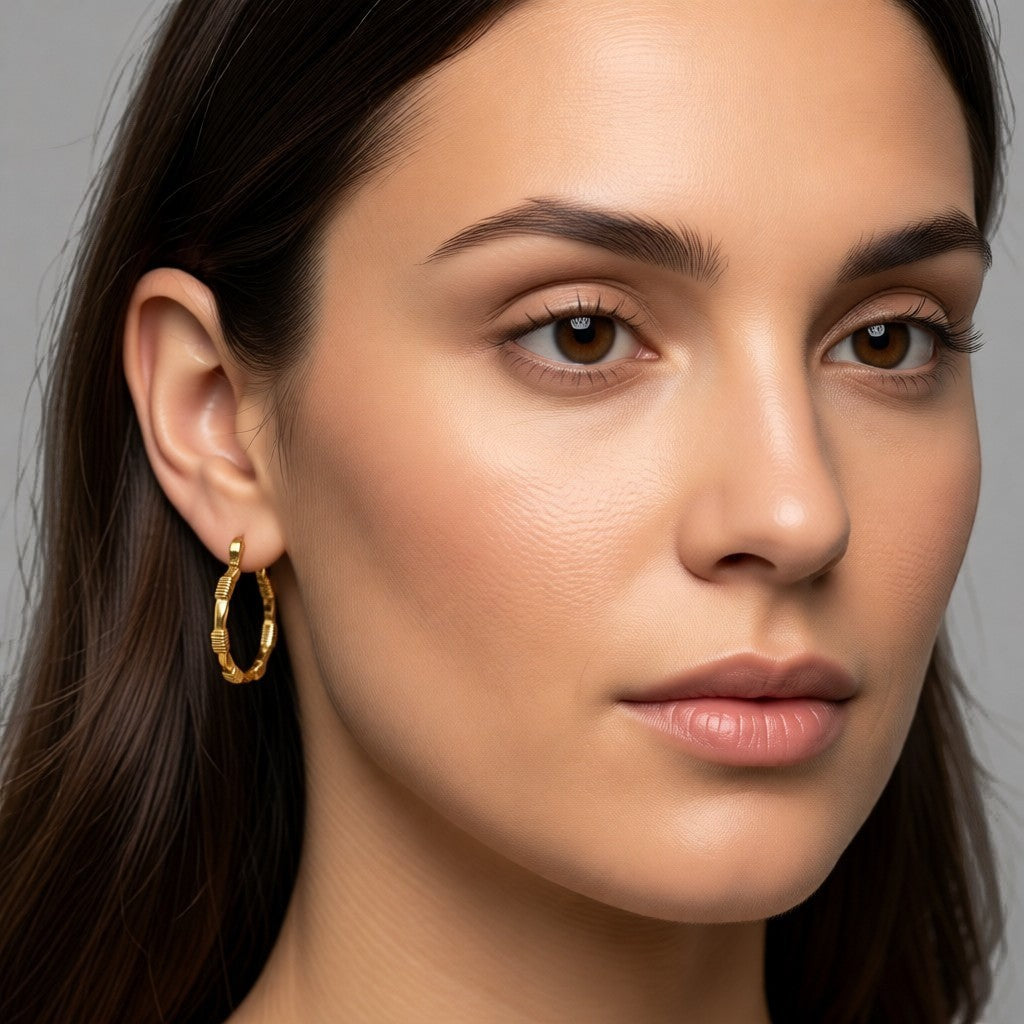 Aramat Jewels gold-tone stainless steel hoop earrings with a block pattern, 25x23mm, featuring a hinge closure.