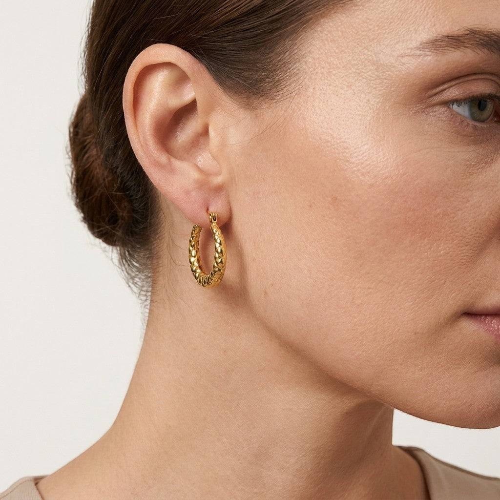 Aramat Jewels gold-coloured stainless steel hoop earrings with a subtle diamond pattern, 22mm diameter.