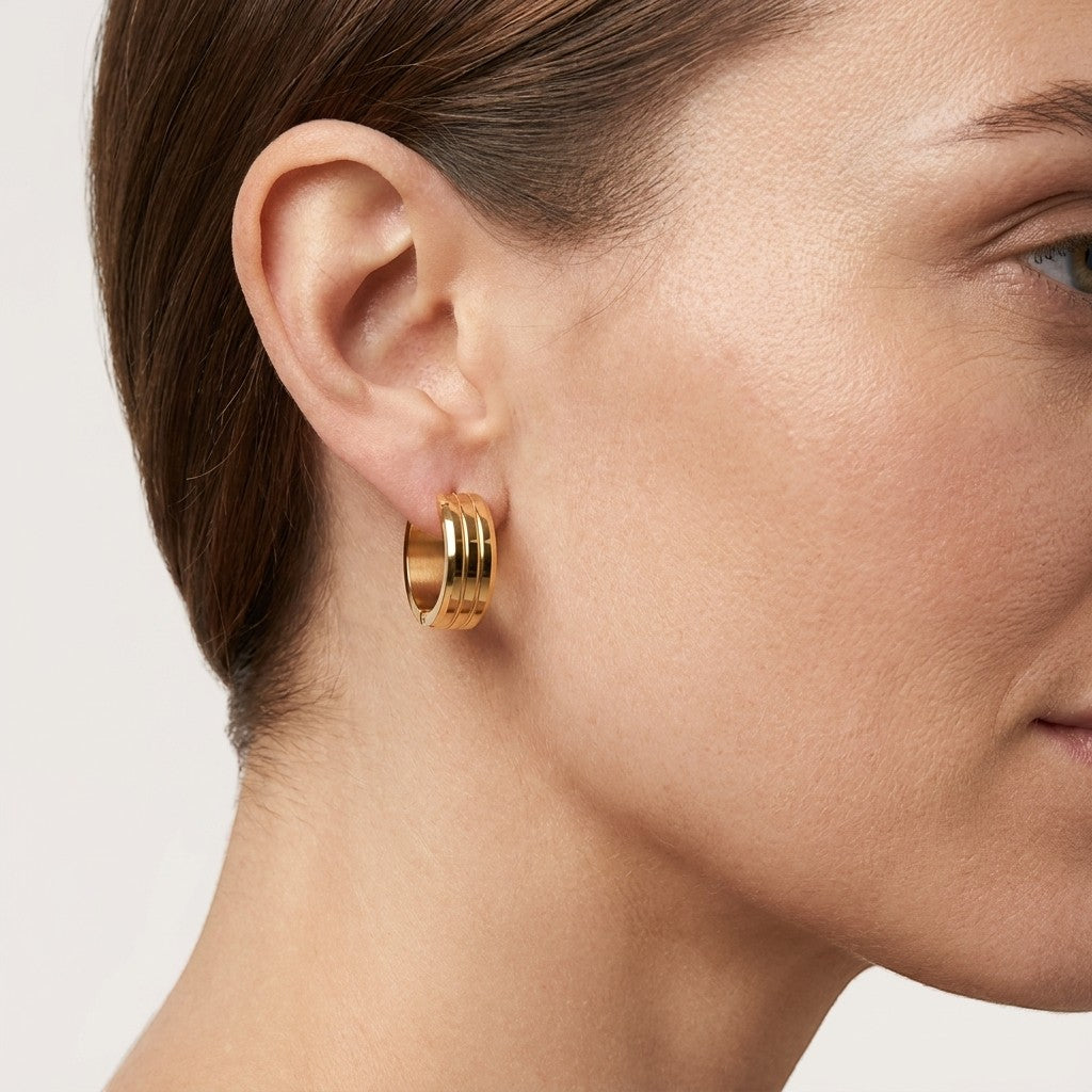 Aramat Jewels gold-tone stainless steel hoop earrings with double stripe detail, worn by a model.