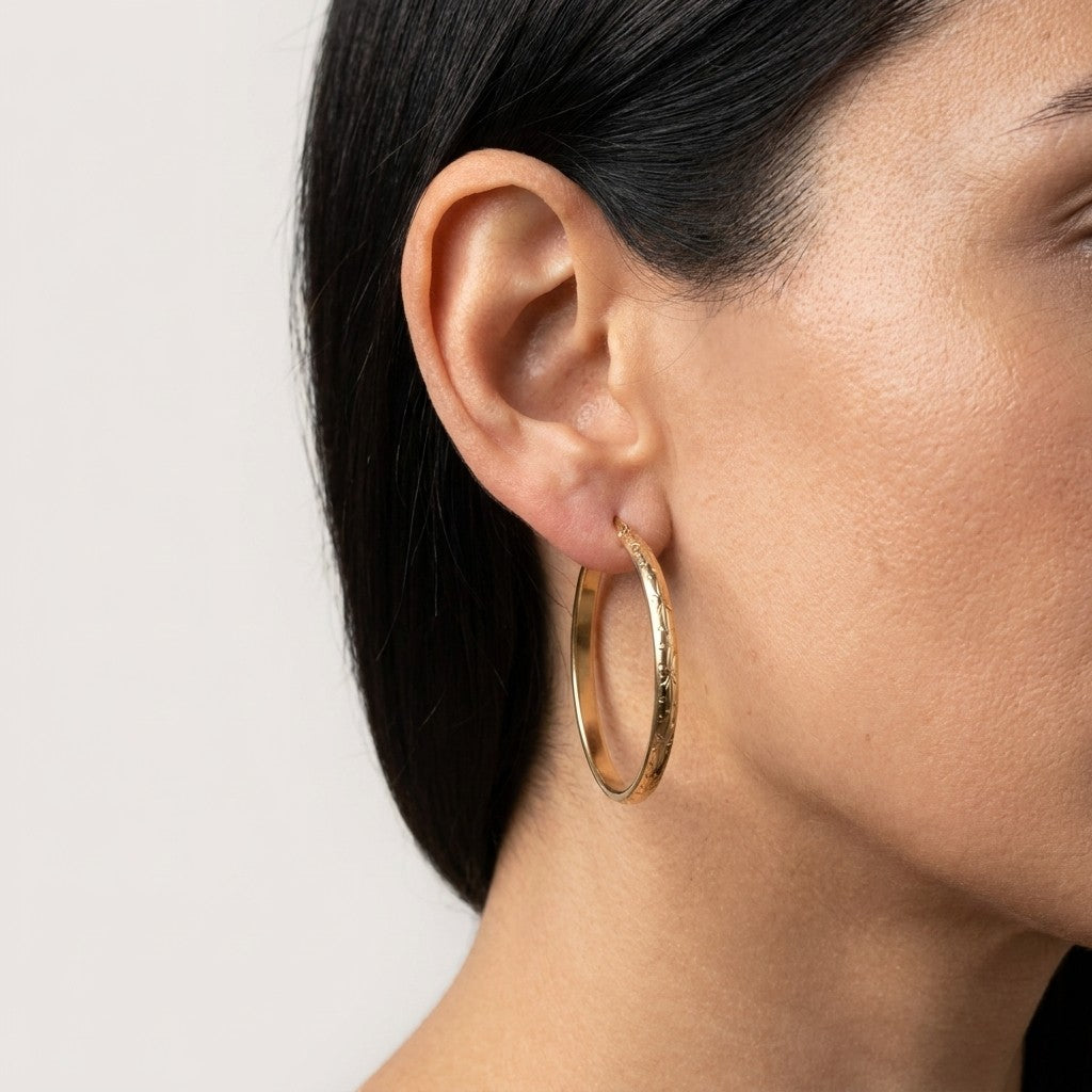 Aramat Jewels gold-tone stainless steel hoop earrings with floral engraving, 40mm diameter.