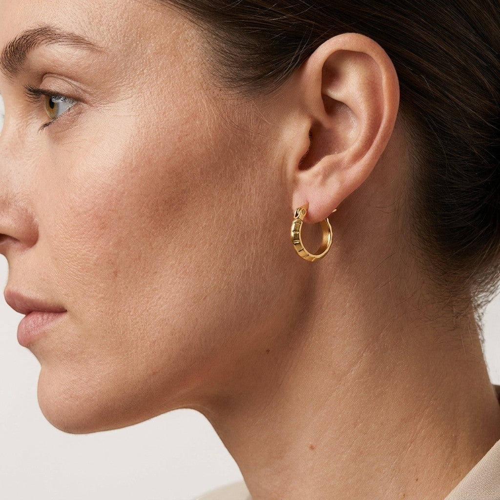 Aramat Jewels small gold hoop earrings with a subtle stripe pattern, 10mm diameter, made of stainless steel.