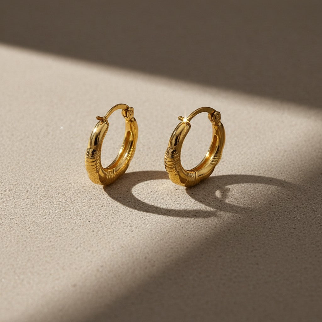Aramat Jewels gold-tone stainless steel hoop earrings with a striped design, 20mm diameter.