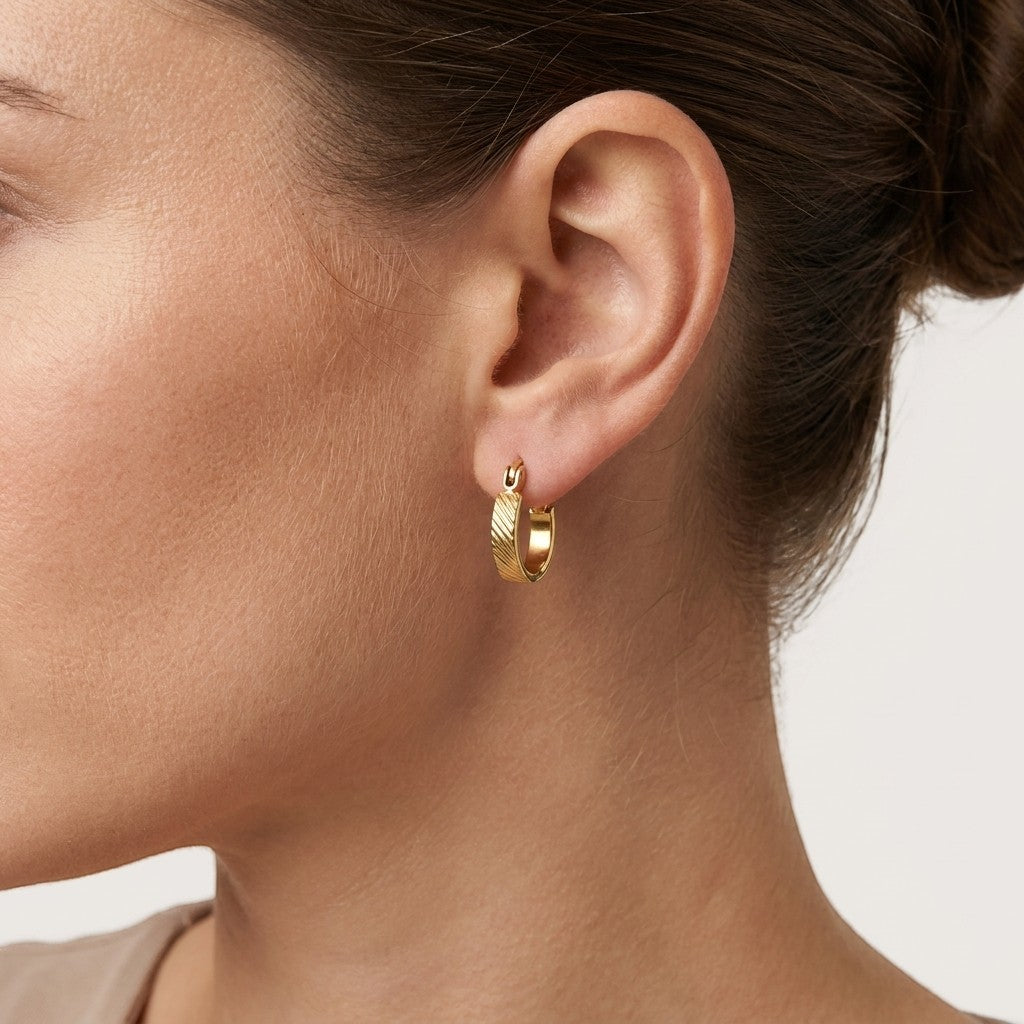 Aramat Jewels small gold stainless steel hoop earrings with a subtle striped pattern, featuring a hinge closure.