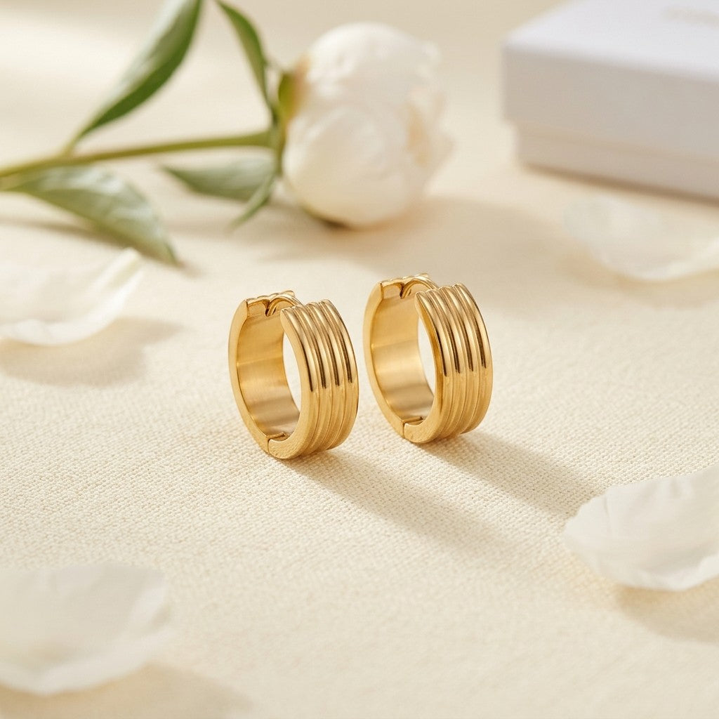 Aramat Jewels gold-tone stainless steel huggie hoop earrings with triple stripe detail, 13mm or 20mm diameter.
