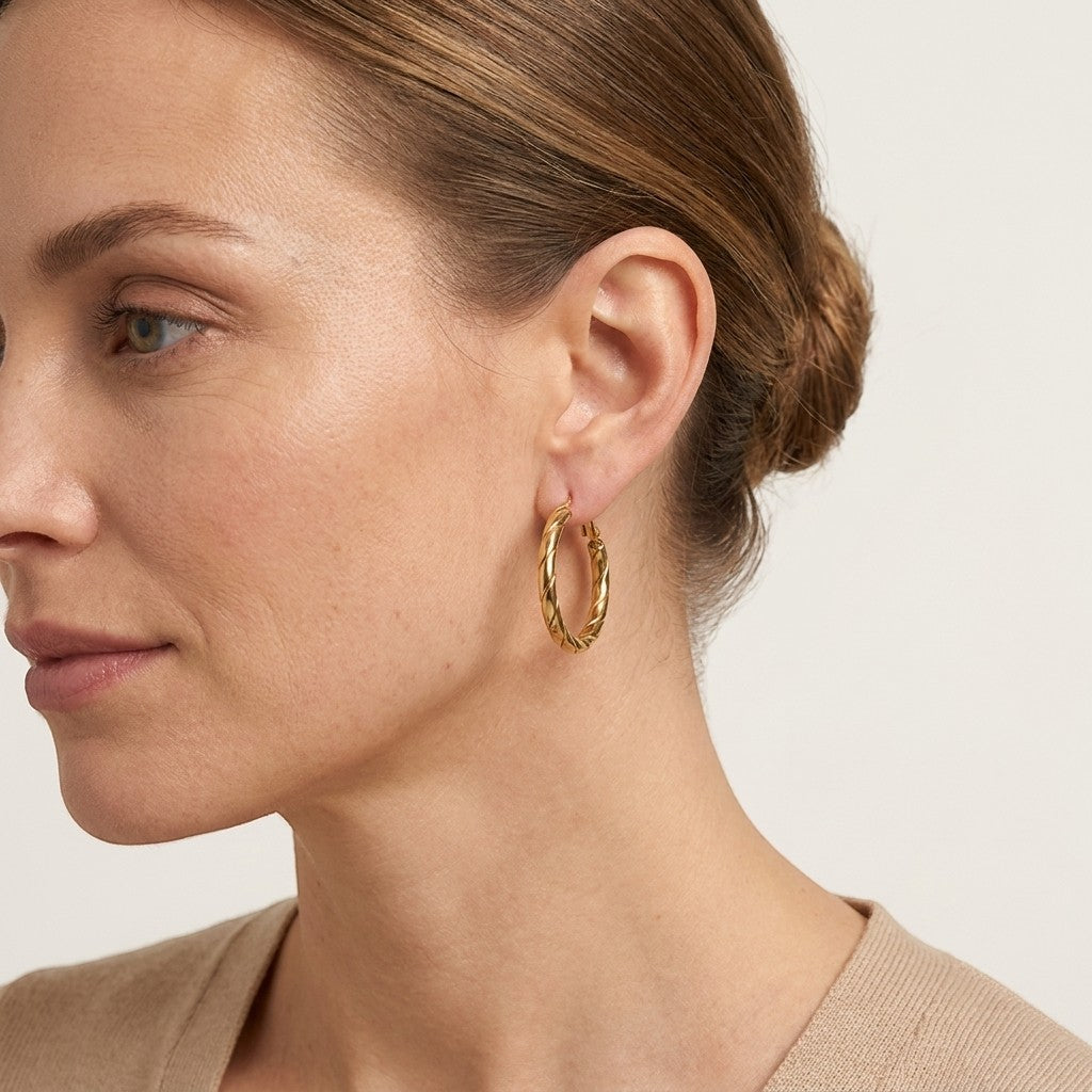 Aramat Jewels gold-tone stainless steel hoop earrings with a twisted rope motif, 25mm diameter.