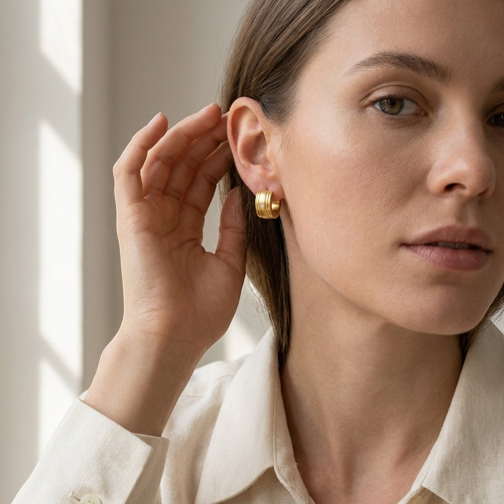 Aramat Jewels gold huggie hoop earrings with a small clear zirconia stone and ribbed texture, 13x7mm.