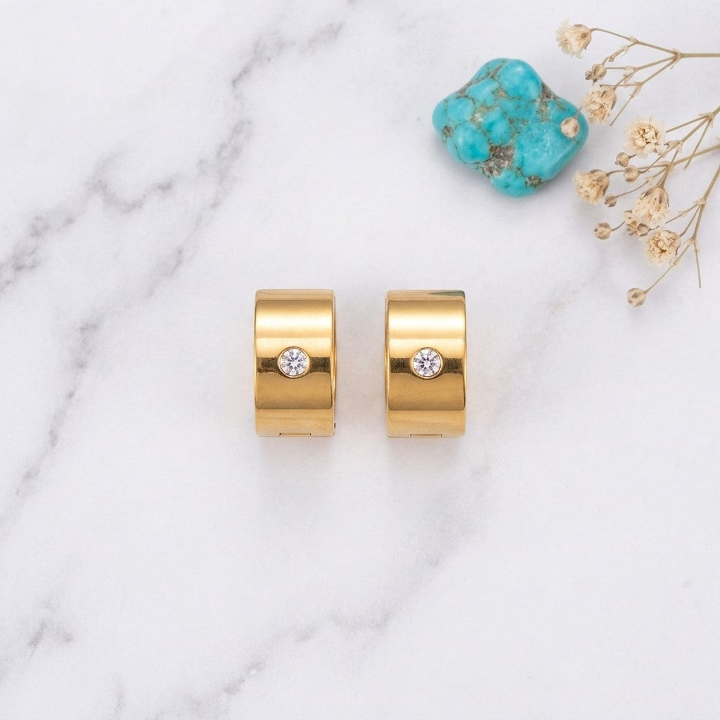 Aramat Jewels gold-tone stainless steel wide hoop earrings with a single clear cubic zirconia stone.
