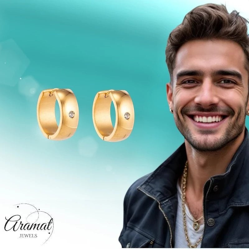 Aramat Jewels gold huggie hoop earrings with a central cubic zirconia stone, worn by a smiling man.