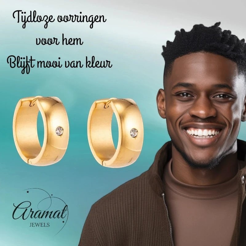 Aramat Jewels gold-tone stainless steel huggie hoop earrings with a central clear cubic zirconia stone, worn by a smiling man.